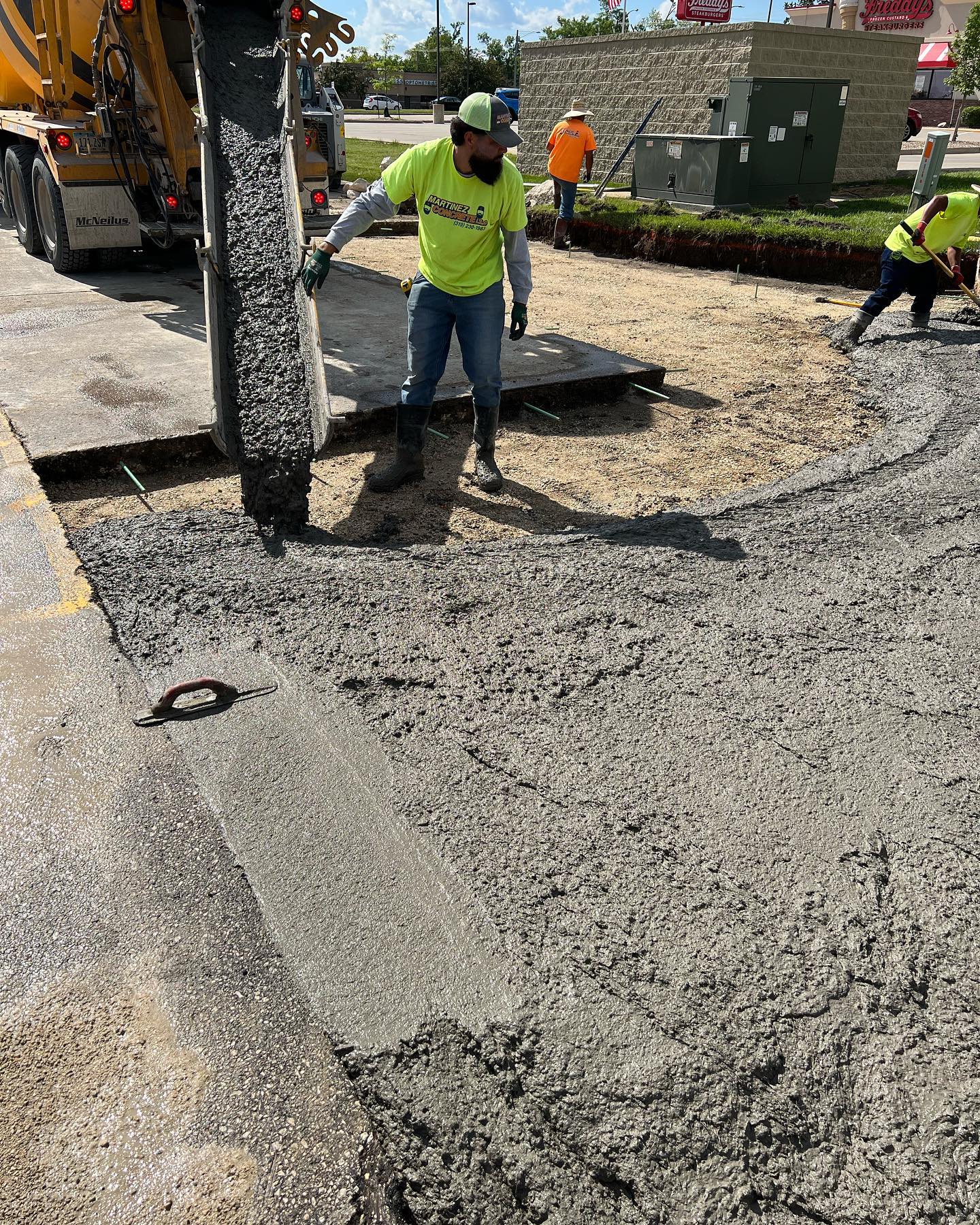 Crew pumping concrete into a curb and island form on a commercial lot