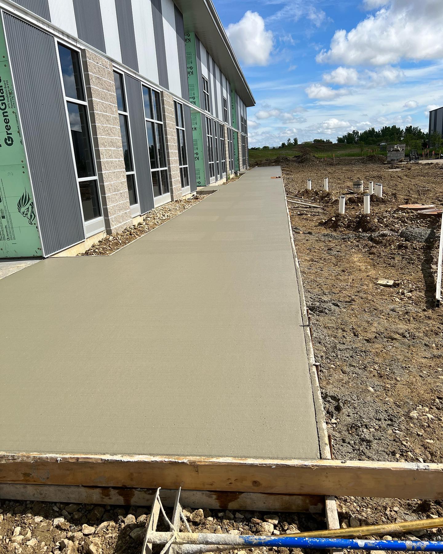 Fresh concrete sidewalk running alongside a commercial building under construction