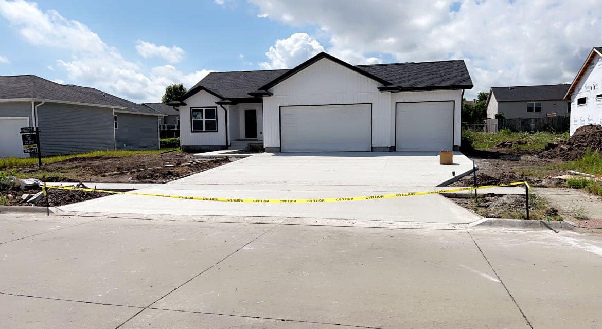 New wide residential concrete driveway in front of a modern farmhouse