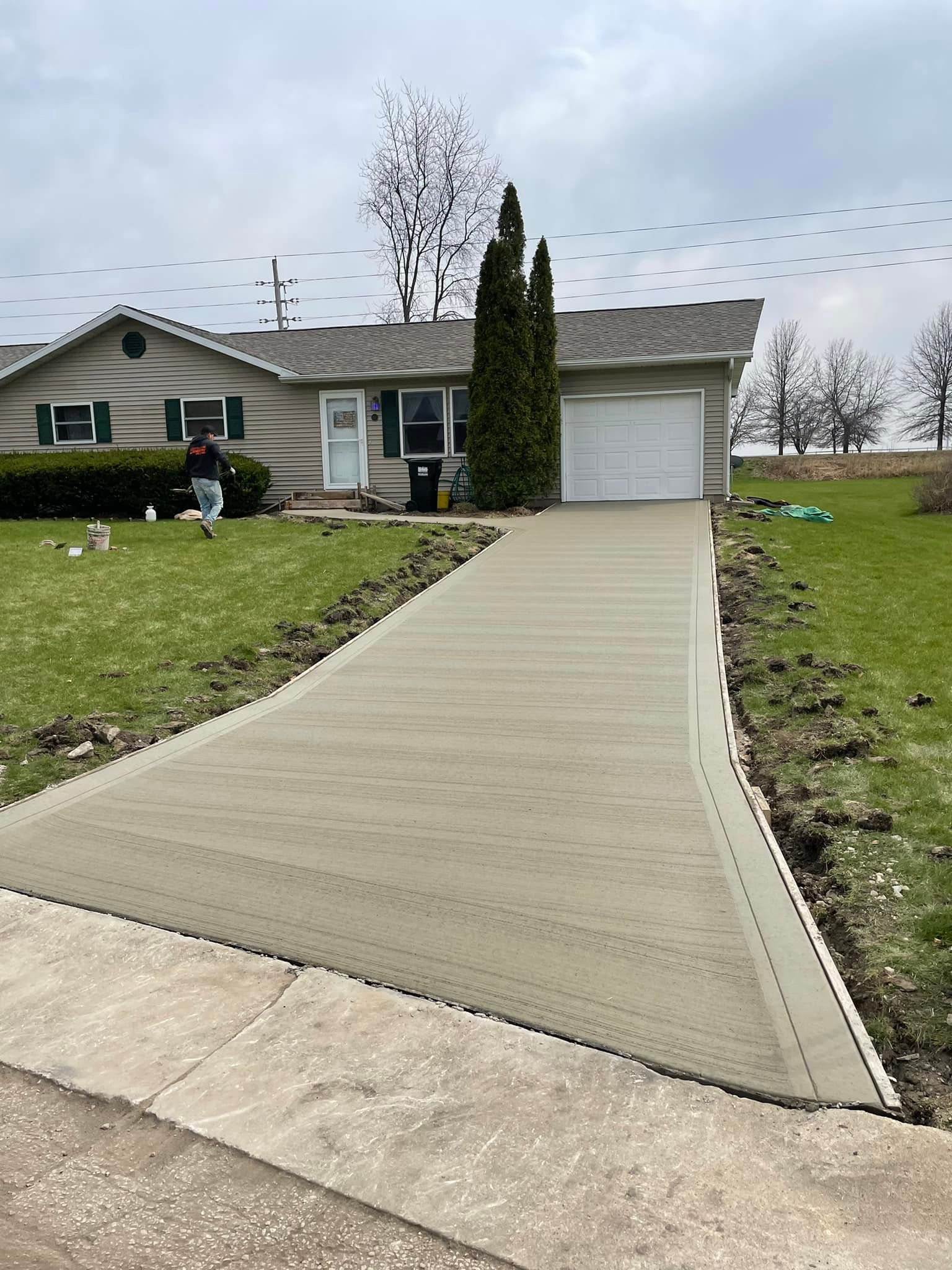 Freshly finished broom-textured driveway leading to a ranch home